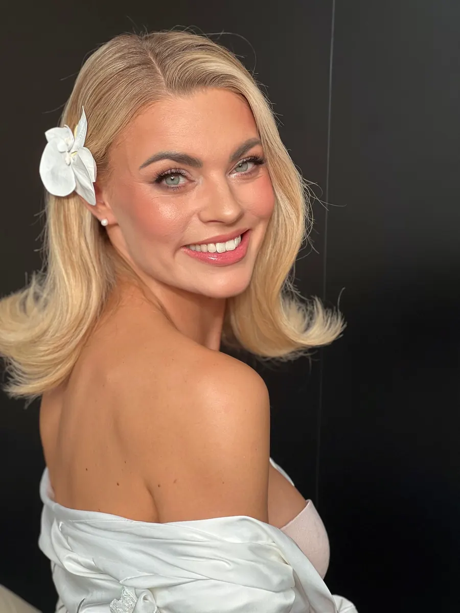 Braut mit blondem Long Bob, Blüte im Haar und strahlendem Braut-Make-up in München