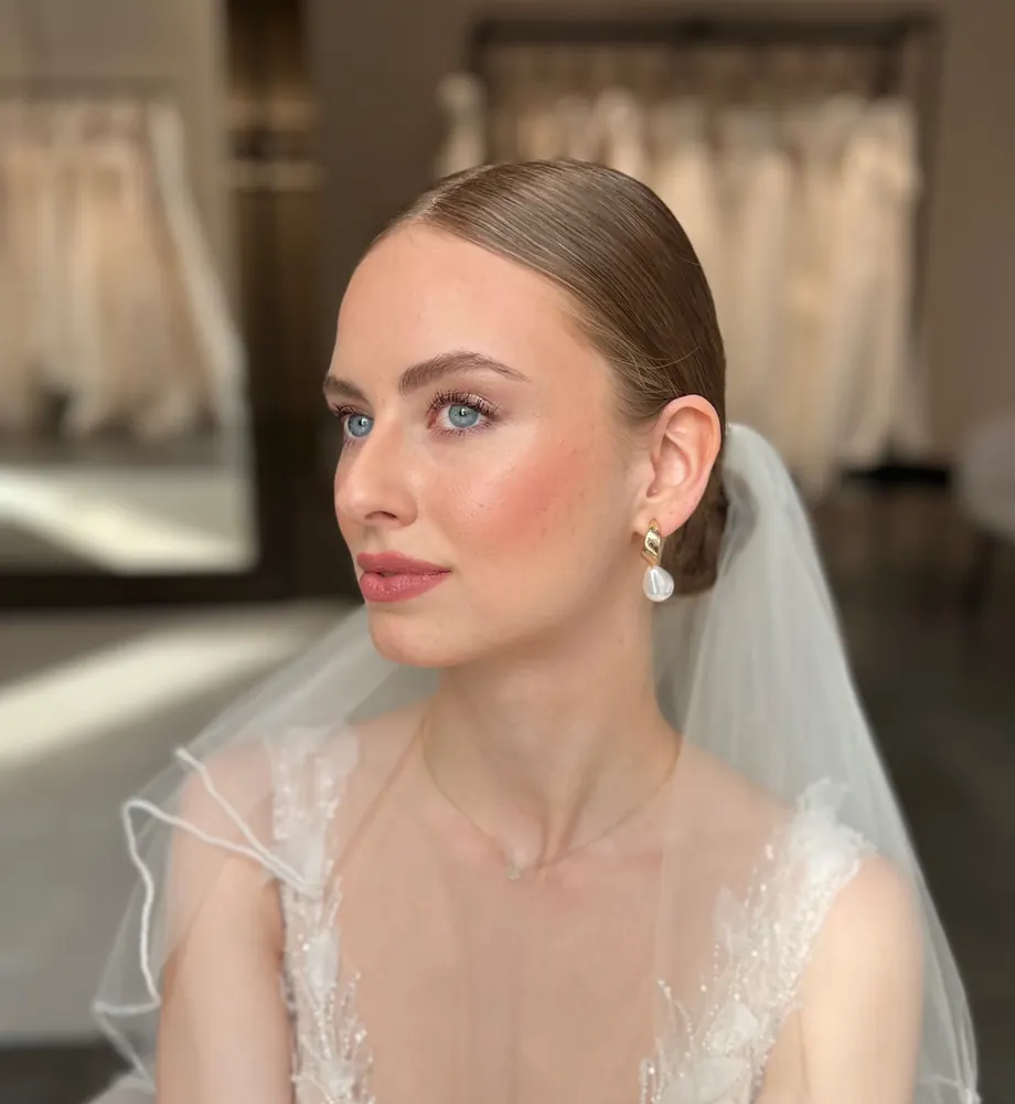 Braut-Make-up mit rosigem Teint und eleganter Hochsteckfrisur, gestylt in München