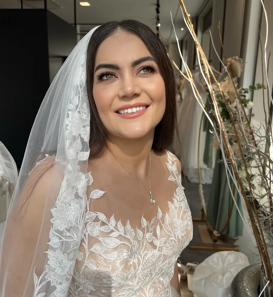 Strahlende Braut im Spitzenkleid mit Schleier nach Haar- und Make-up-Styling in München
