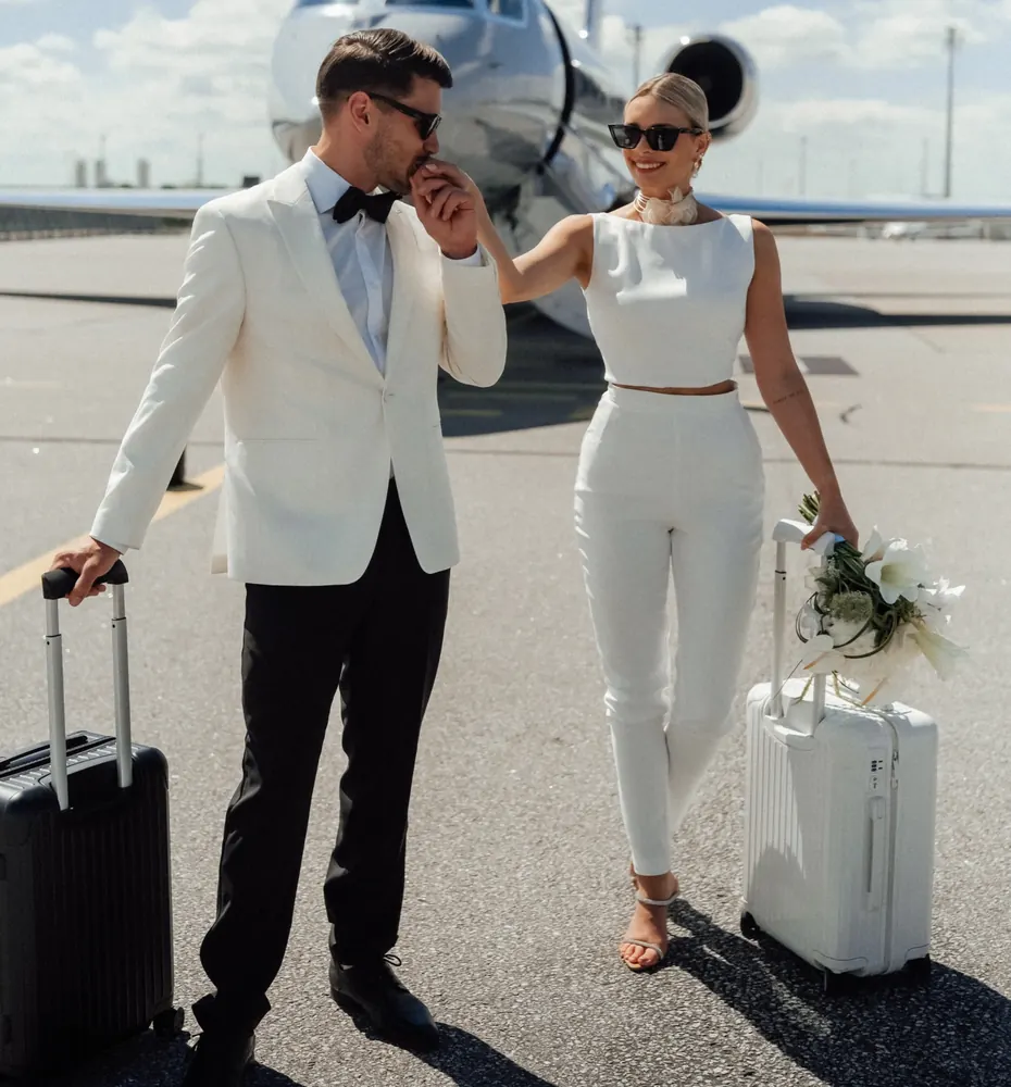 Brautpaar mit Koffern vor dem Privatjet auf dem Weg zur Destination Wedding